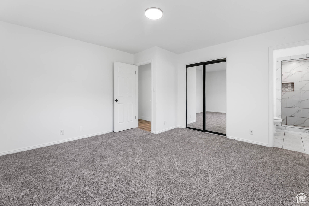 Unfurnished bedroom with carpet floors, a closet, and ensuite bathroom