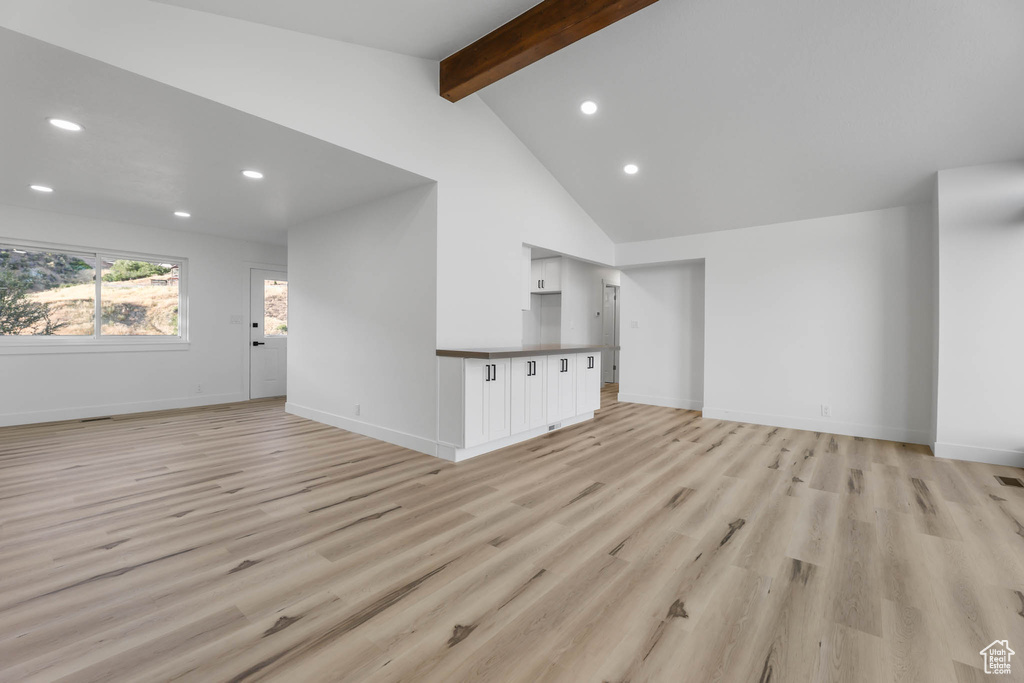 Unfurnished living room with beamed ceiling, recessed lighting, light wood-style floors, and high vaulted ceiling