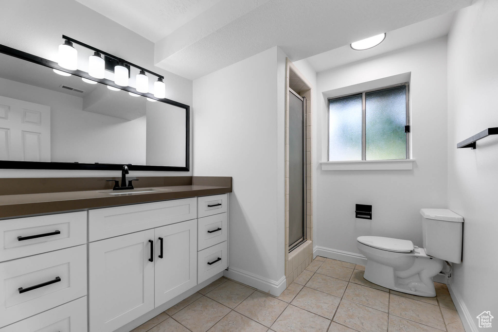 Bathroom featuring vanity, an enclosed shower, and tile patterned flooring