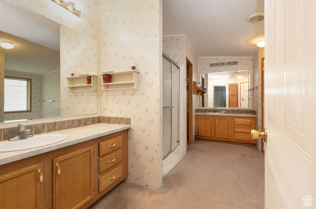 Full bath with wallpapered walls, a shower stall, vanity, and a textured ceiling