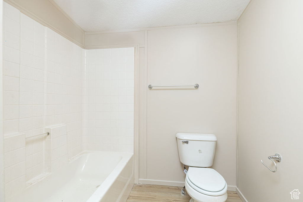 Bathroom featuring wood finished floors, a textured ceiling, and  shower combination