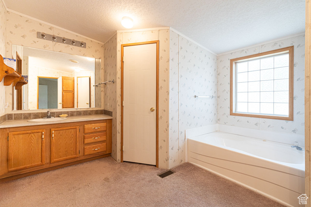 Full bath with crown molding, vanity, carpet, a garden tub, and wallpapered walls