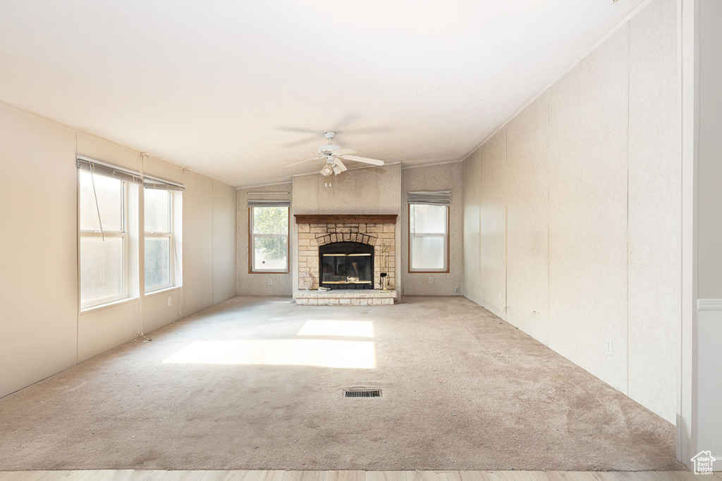 Unfurnished living room featuring ceiling fan, carpet floors, a glass covered fireplace, and lofted ceiling
