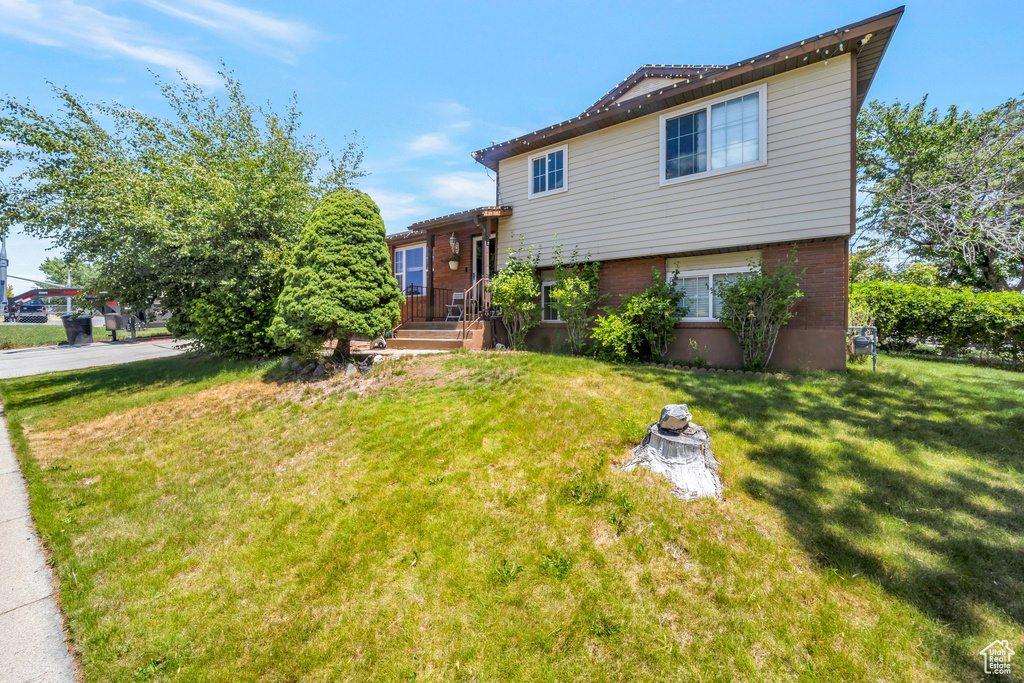 Tri-level home featuring a front yard and brick siding