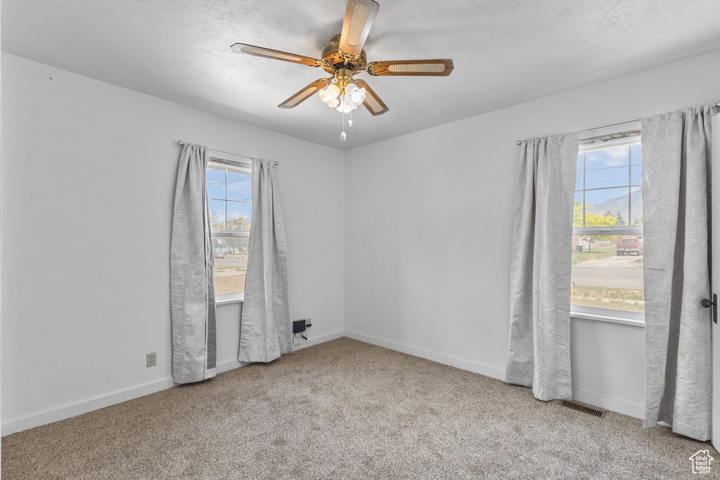 Unfurnished room with a ceiling fan and carpet