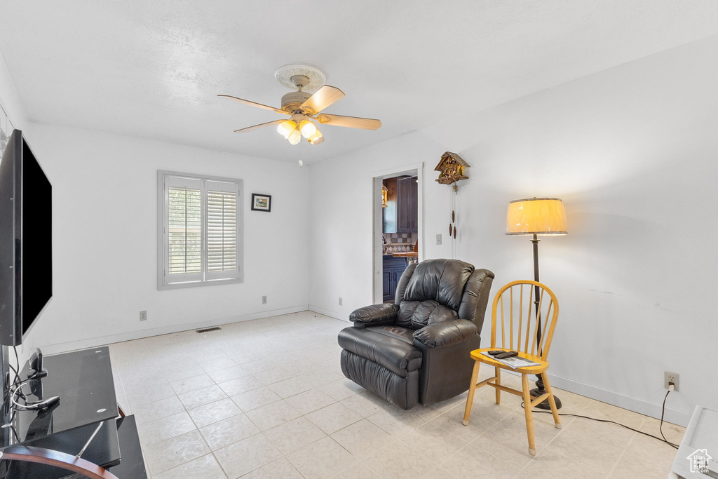 Living area with ceiling fan and baseboards