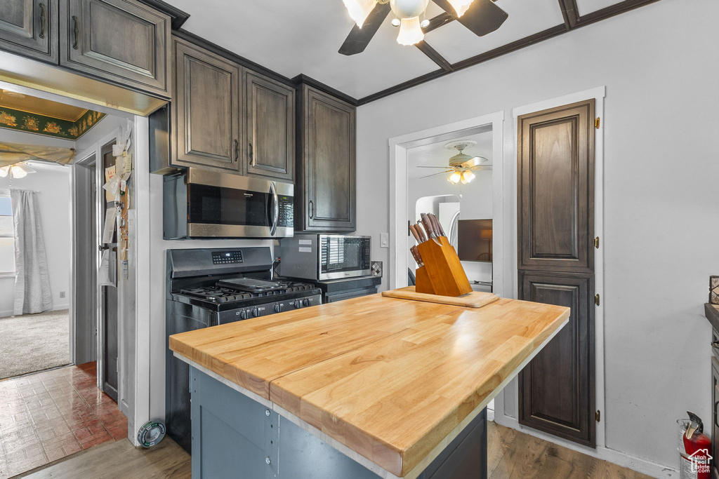 Kitchen with a ceiling fan, wooden counters, stainless steel microwave, and gas stove