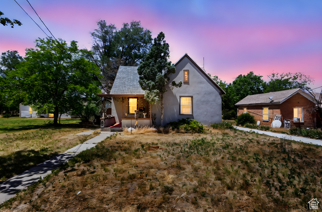 View of front of property featuring covered porch, stucco siding, and a front lawn