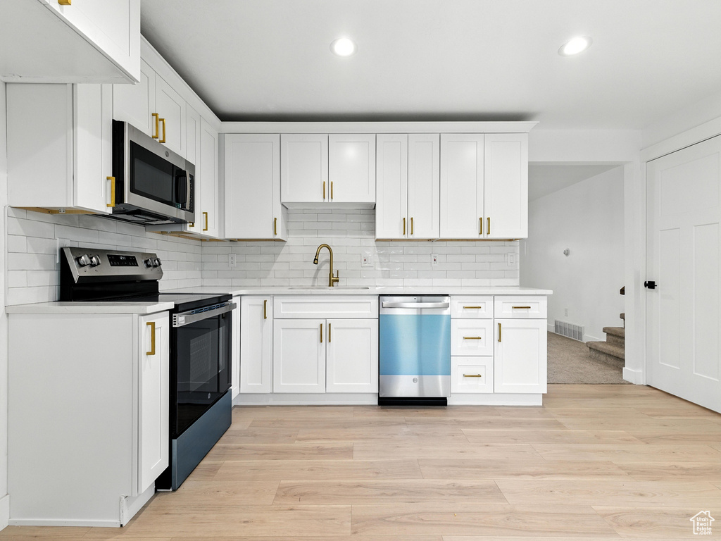 Kitchen featuring stainless steel appliances, light countertops, recessed lighting, and decorative backsplash