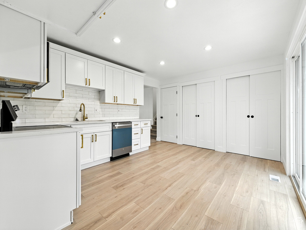 Kitchen featuring dishwasher, light countertops, decorative backsplash, white cabinets, and recessed lighting