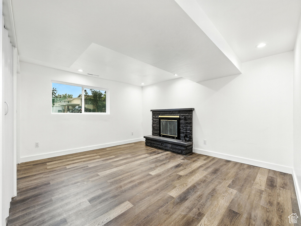 Unfurnished living room featuring a stone fireplace, wood finished floors, and recessed lighting