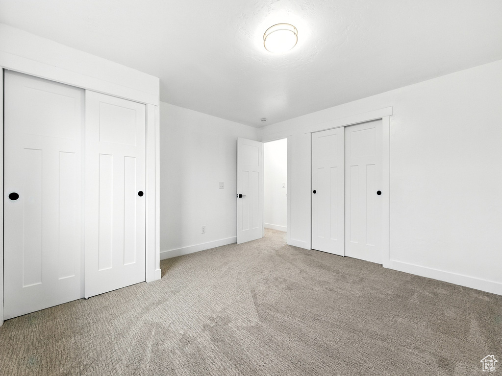 Unfurnished bedroom featuring carpet and multiple closets