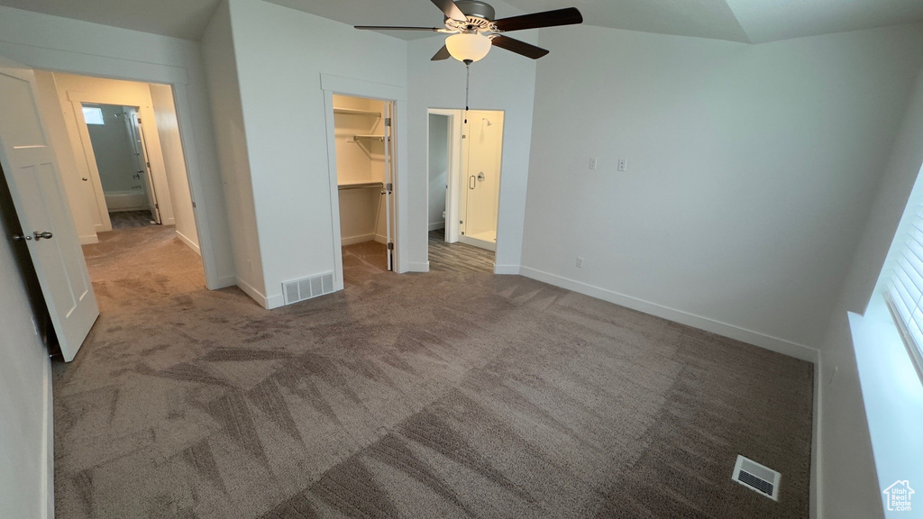 Unfurnished bedroom featuring a walk in closet, carpet flooring, a closet, and ceiling fan