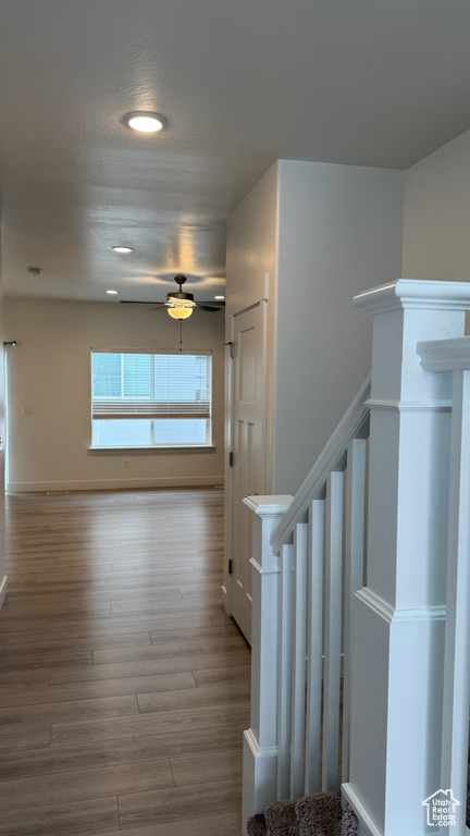 Corridor featuring recessed lighting, wood finished floors, and stairway