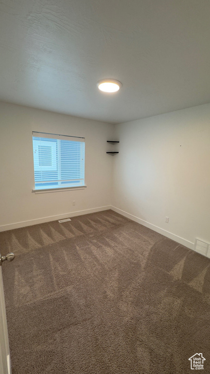 Unfurnished room with baseboards and dark colored carpet