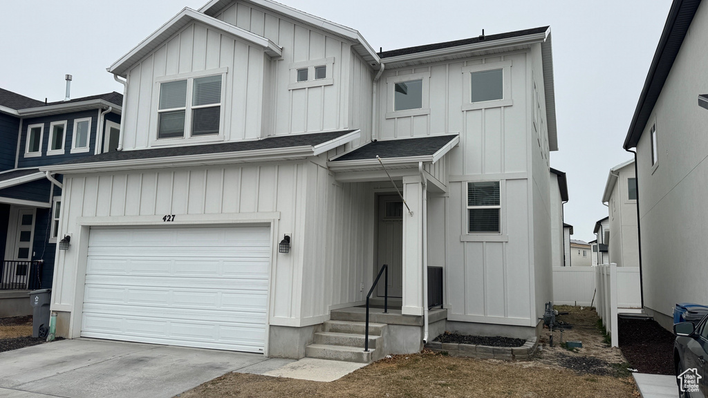 View of front facade with board and batten siding, a garage, and concrete driveway