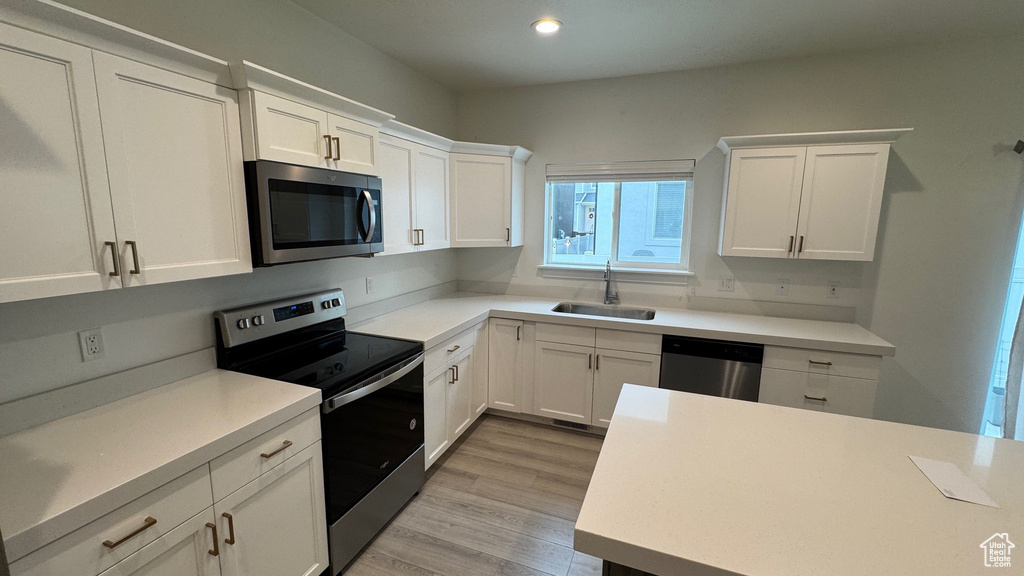 Kitchen featuring appliances with stainless steel finishes, white cabinetry, light countertops, and recessed lighting