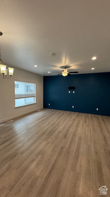Unfurnished living room featuring wood finished floors, a chandelier, a ceiling fan, and recessed lighting