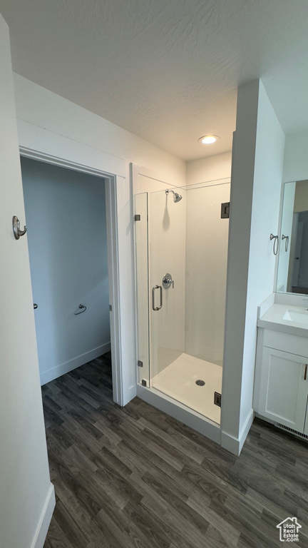 Bathroom featuring wood finished floors, a stall shower, vanity, and recessed lighting