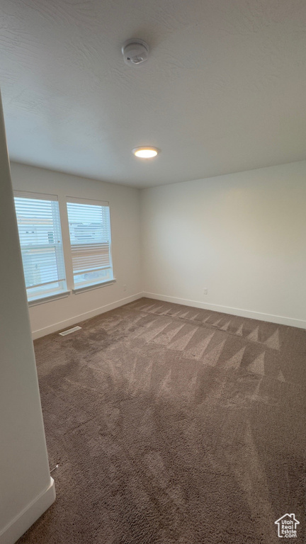Carpeted spare room with baseboards and a smoke detector