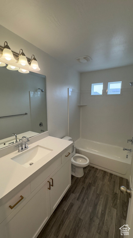 Full bathroom featuring wood finished floors, vanity, and bathing tub / shower combination
