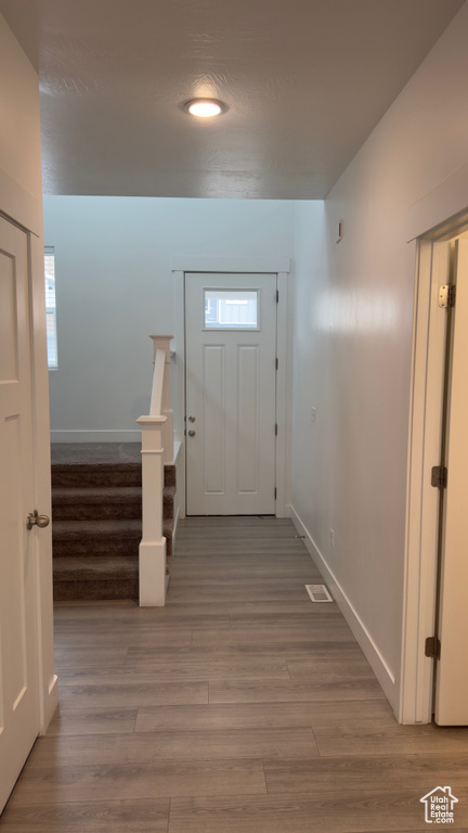 Doorway to outside with light wood-style flooring and stairway