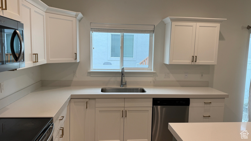 Kitchen featuring dishwasher, white cabinets, and light countertops