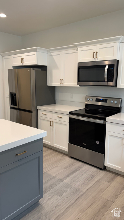 Kitchen with appliances with stainless steel finishes, light wood-style floors, light countertops, white cabinetry, and recessed lighting