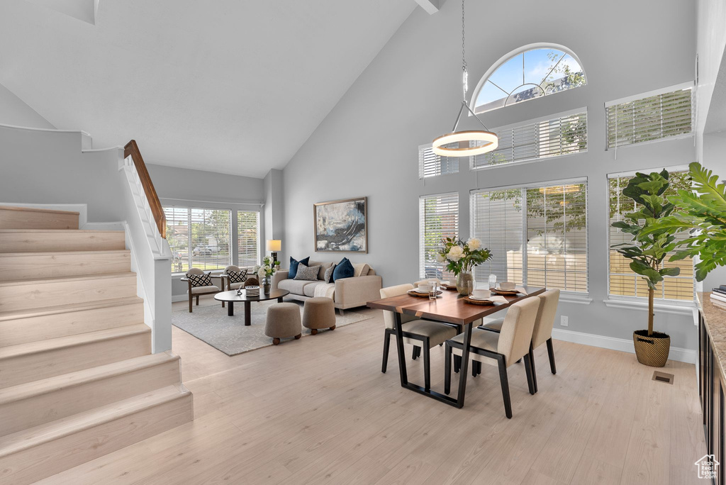 Dining room featuring high vaulted ceiling, stairway, and light wood finished floors
