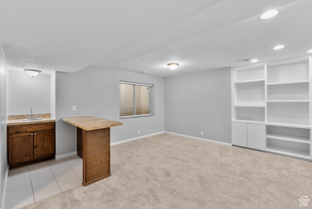 Indoor wet bar with light colored carpet, a textured ceiling, recessed lighting, and light tile patterned floors