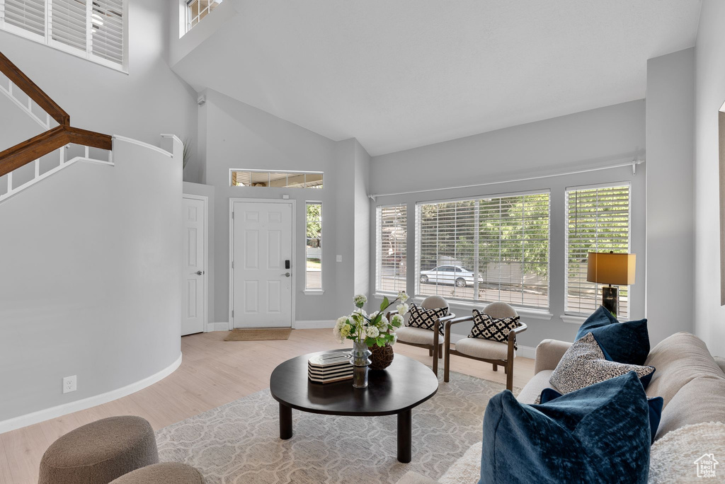 Living room with wood finished floors, plenty of natural light, high vaulted ceiling, and stairs