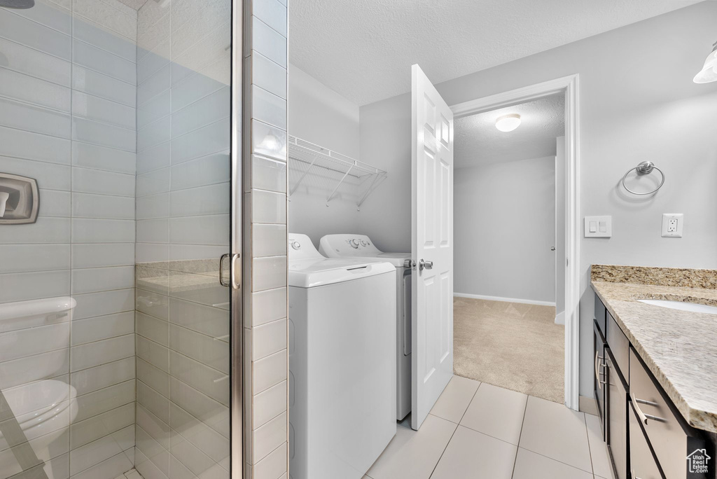 Washroom featuring independent washer and dryer, light carpet, and light tile patterned floors