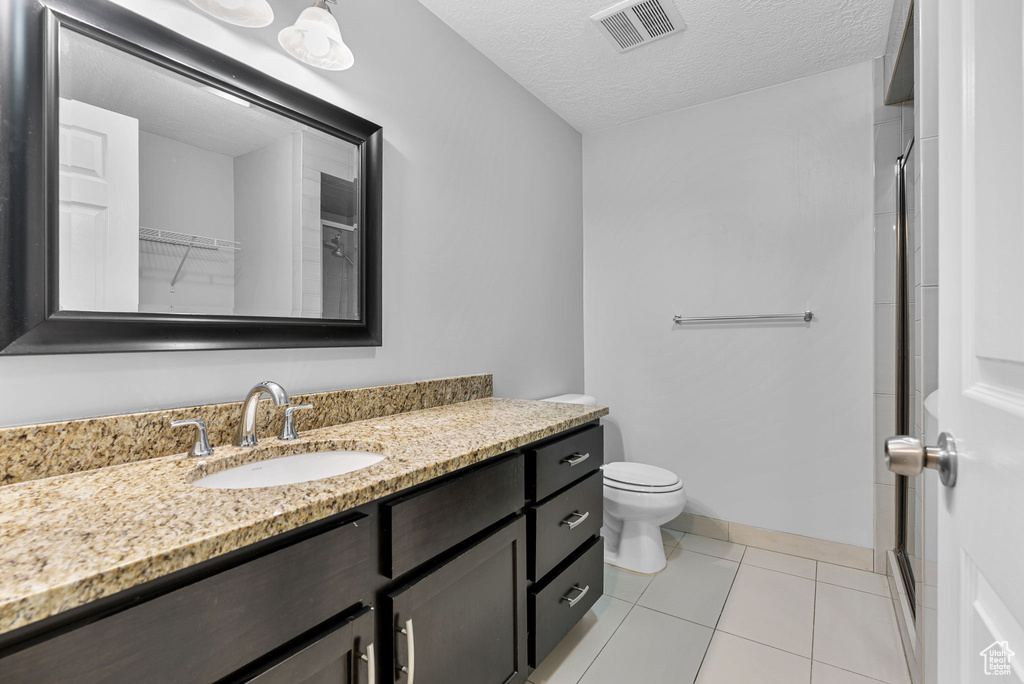 Full bath featuring vanity, a shower stall, tile patterned flooring, and a textured ceiling