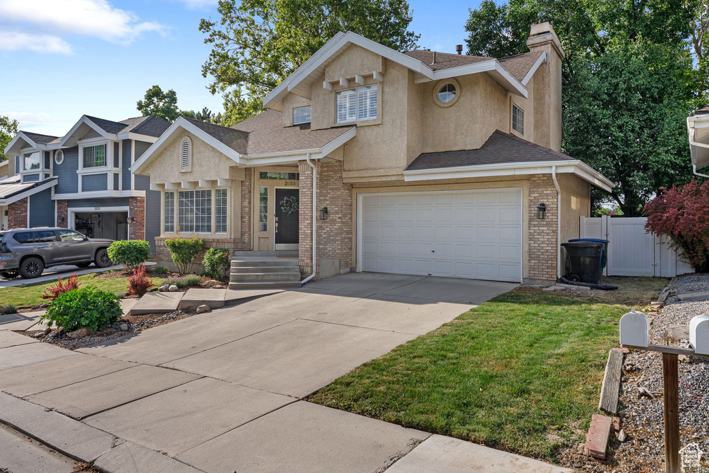 Traditional-style home featuring stucco siding, concrete driveway, a shingled roof, a garage, and brick siding