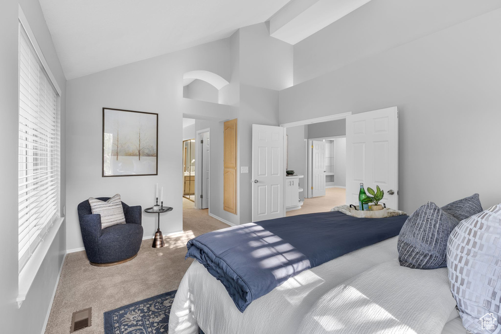 Bedroom with light carpet, high vaulted ceiling, and connected bathroom