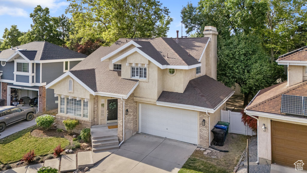 View of front of home featuring stucco siding, roof with shingles, and a chimney
