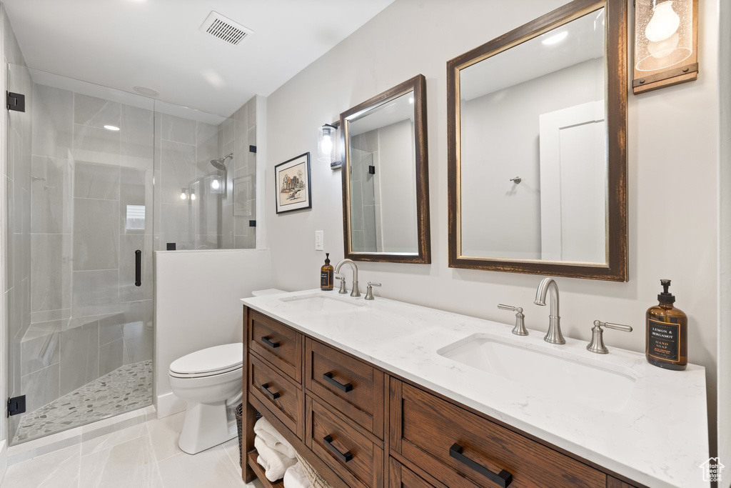 Bathroom with a stall shower, double vanity, and tile patterned floors