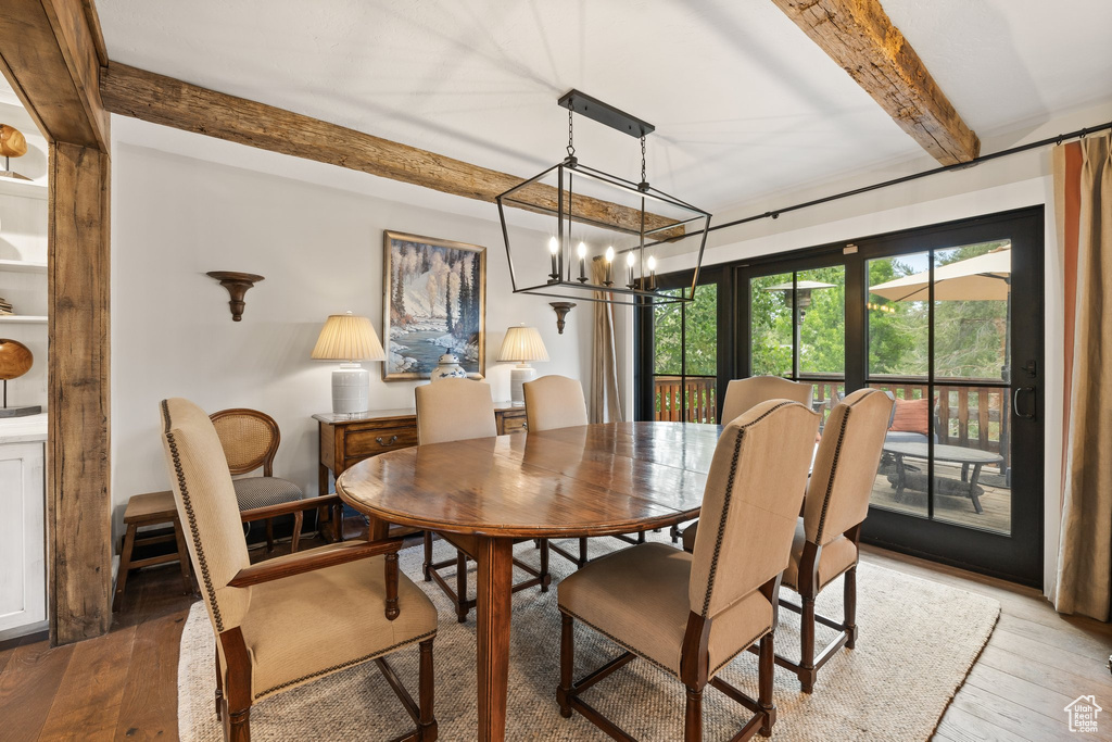 Dining space with beam ceiling, light wood-type flooring, and a chandelier