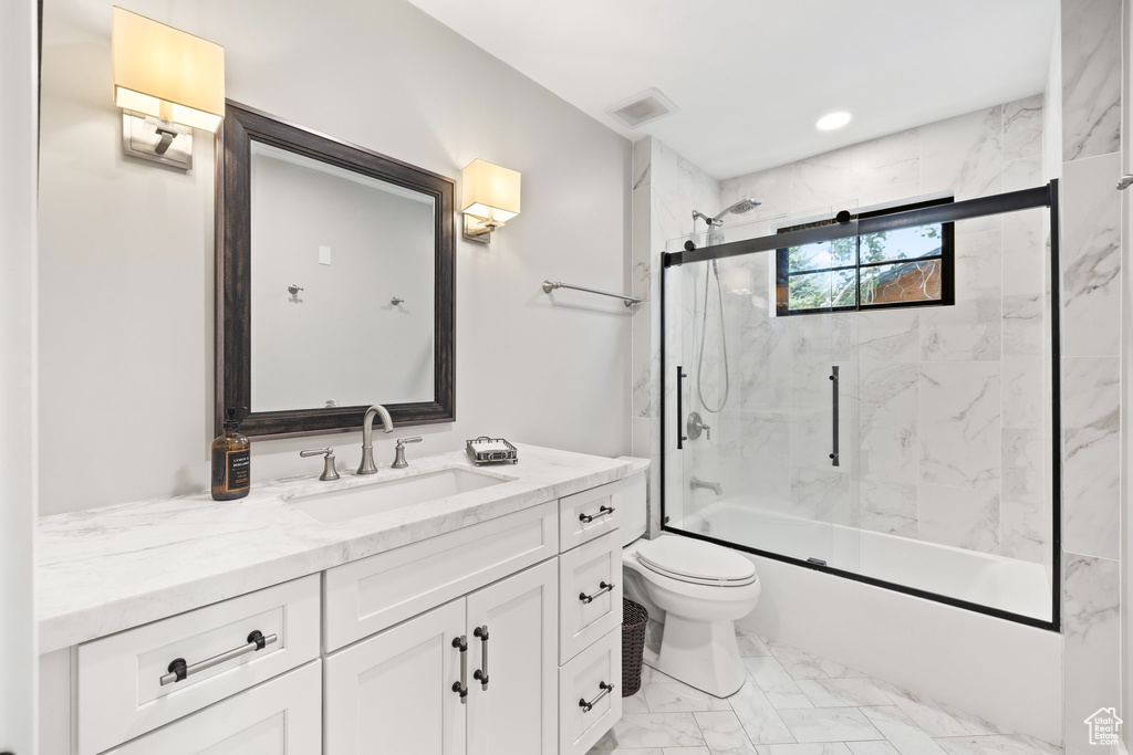 Bathroom featuring marble finish floors, vanity, and enclosed tub / shower combo