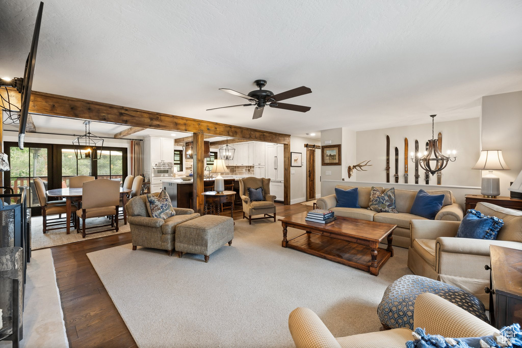 Living area featuring dark wood finished floors, ceiling fan, and a chandelier