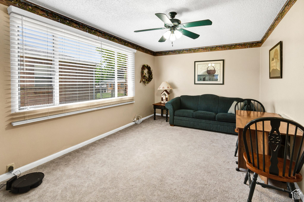 Carpeted living room featuring a textured ceiling and a ceiling fan