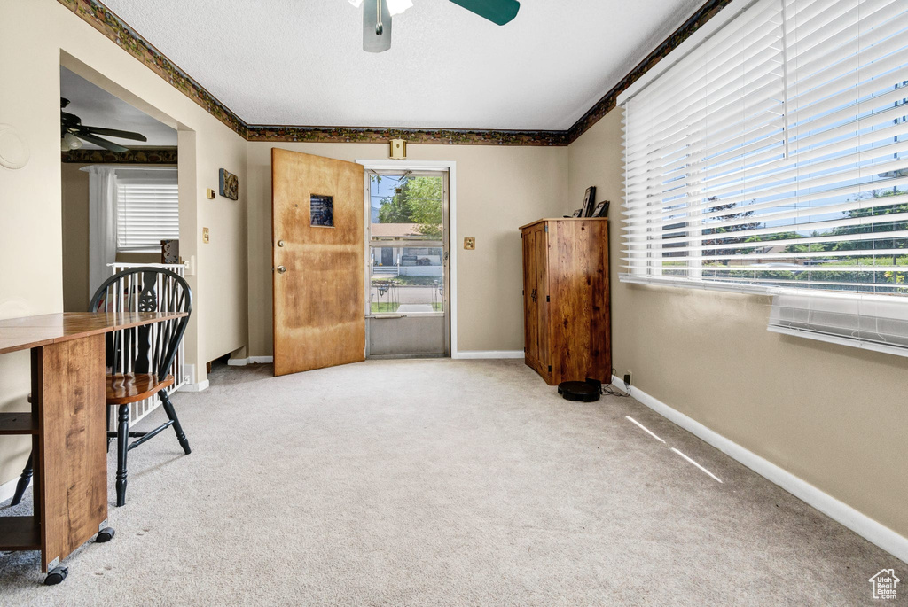 Carpeted home office with ceiling fan and baseboards