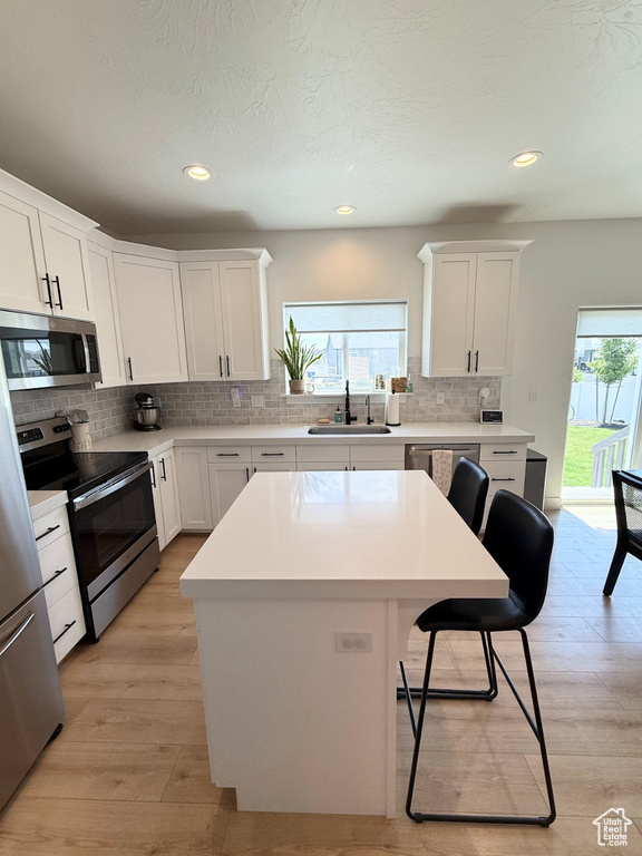 Kitchen with stainless steel appliances, plenty of natural light, a breakfast bar, backsplash, and recessed lighting