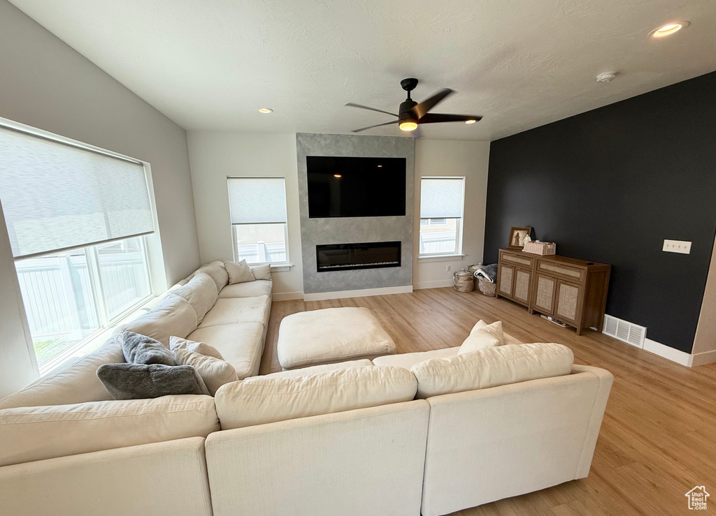 Living area with ceiling fan, light wood-type flooring, a large fireplace, and recessed lighting