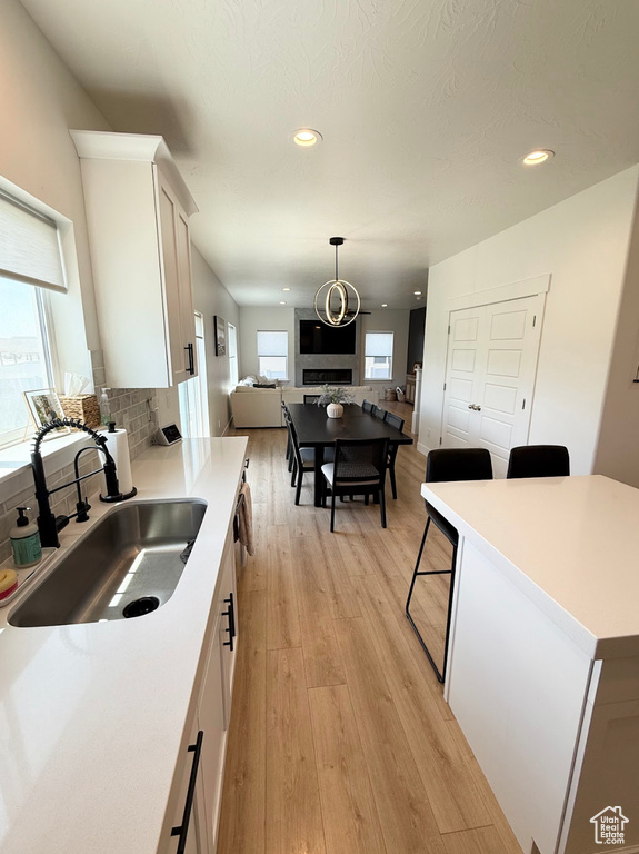 Kitchen featuring open floor plan, white cabinets, tasteful backsplash, light wood-style flooring, and recessed lighting