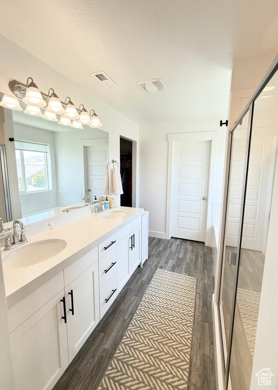 Full bath featuring a stall shower, double vanity, wood finished floors, and a spacious closet