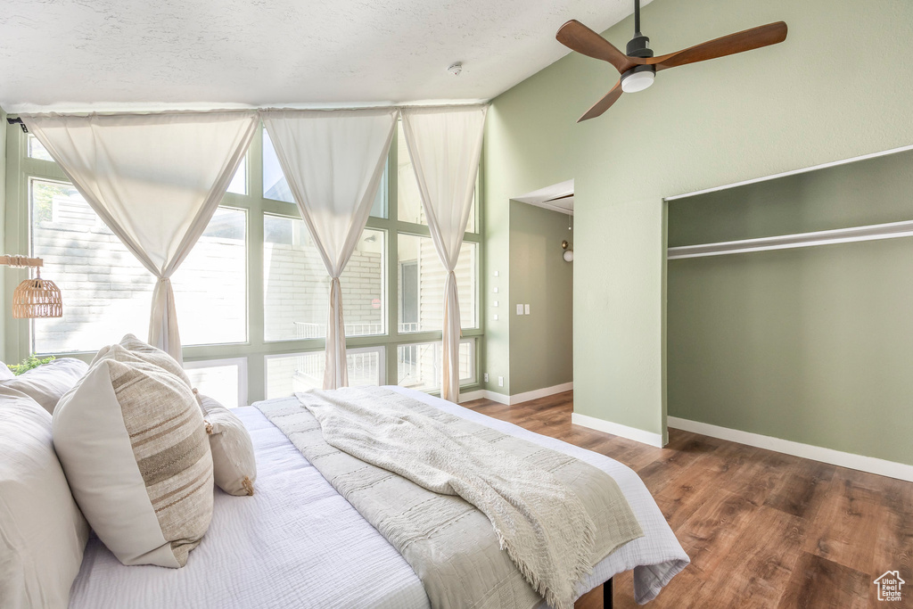 Bedroom featuring lofted ceiling, wood finished floors, a closet, ceiling fan, and a textured ceiling