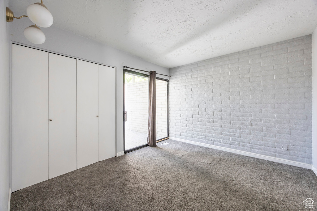 Unfurnished bedroom with carpet floors, a textured ceiling, access to outside, and a closet