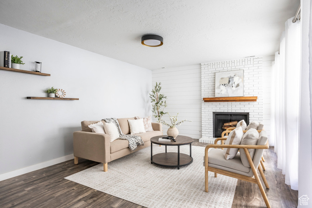 Living area with dark wood-style flooring and a brick fireplace