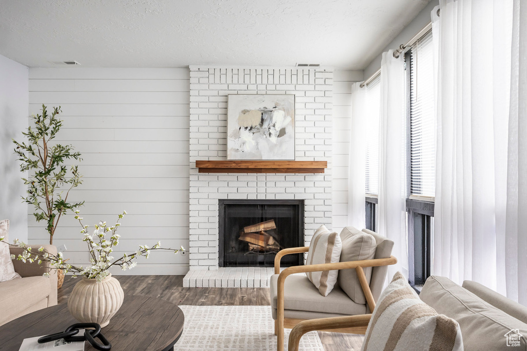 Living area featuring wood finished floors, a fireplace, and a textured ceiling